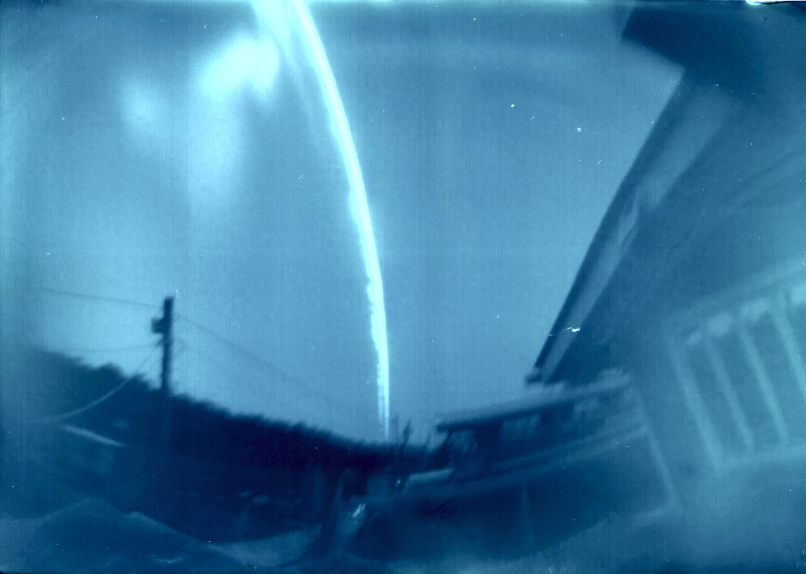 Cyanotype-toned west-facing solargraph with vertical Sun arc and landscape silhouette